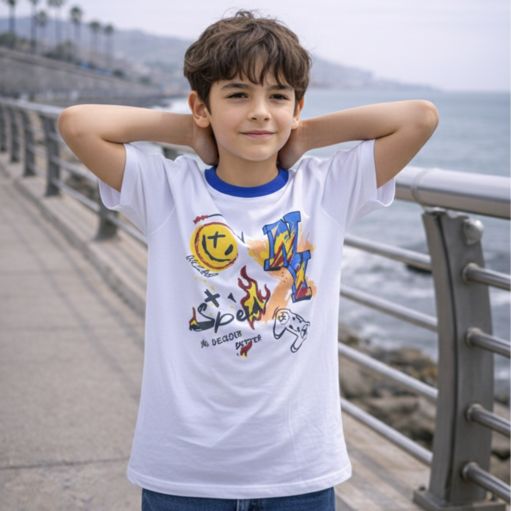 Niño con polo blanco de manga corta, cuello azul y estampado multicolor, junto a una baranda.