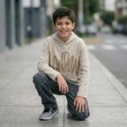Niño con hoodie London 2025 beige ANG Kidz – look streetwear con jean gris