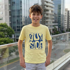 Vista frontal del polo amarillo para niño Think Outside con estampado azul, combinado con jean gris.
